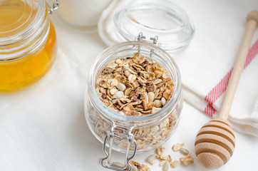 Top view breakfast of homemade granola cereal with nuts and fruit, honey with drizzlier on white background. Healthy food, Diet, Detox, Clean Eating, Vegetarian concept.