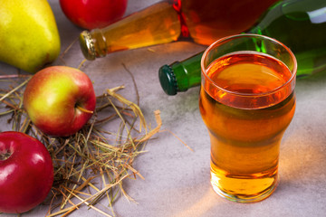 Glass and bottles of apple and pear cider with fruits