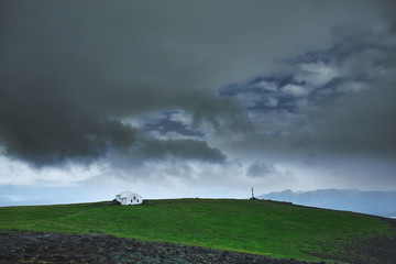 Naklejka na ściany i meble Travel to Iceland. The charming rustic rural house on the cloudy sky background