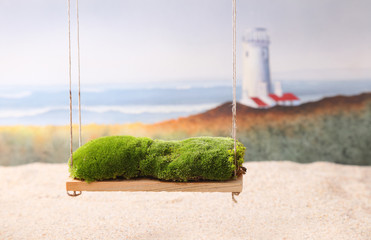 A newborn background backdrop with moss on a swing over a sandy beach with a lighthouse and ocean...