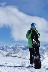 snowboarder standing with snowboard in the mountains.