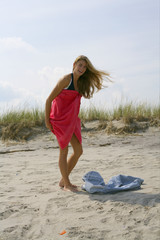 Naklejka premium Young blond woman is changing clothes at the beach