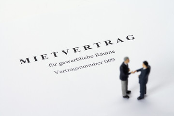 Businessmen figurines standing on a rental agreement shaking hands