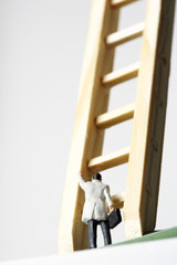 Businessman figurine in front of a ladder
