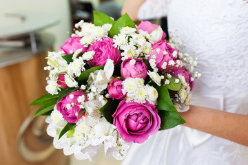 Bride holding beautiful wedding bouquet with pink roses, closeup