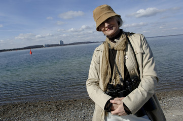 Obraz premium Portrait of a mature woman with a field glasses at Baltic Sea beach
