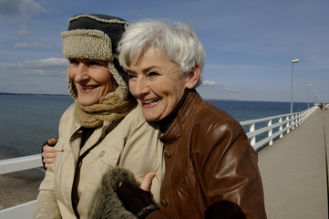 Two laughing mature women walking along the Baltic Sea