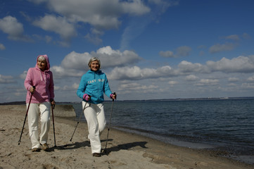 Two mature women Nordic walking at Baltic Sea beach