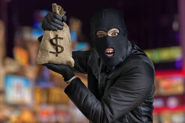 Happy robber is showing stolen bag full of money at night.
