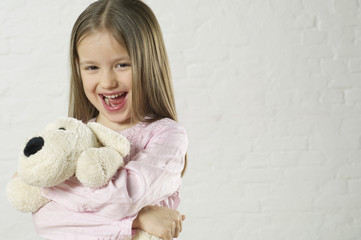 Girl holding a stuffed animal and laughing at camera