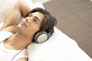 Relaxed young man listening to music by earphones