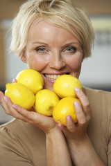 Mature woman holding a medium group of lemons in her hands, close-up