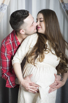 A gentle kiss-happy couple awaiting the birth of their child.