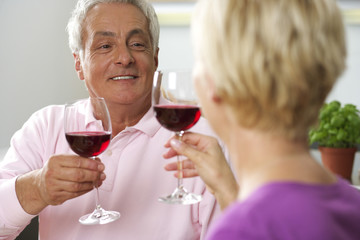 Gray-haired man and blonde woman clinking glasses, low angle view
