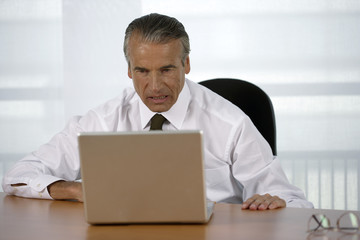 Nervous senior businessman using a laptop