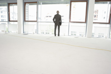 Fototapeta premium Elderly manager in an empty office, looking out the window