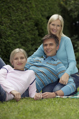 Fototapeta premium Father, mother and daughter lying on a meadow in a park