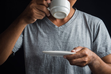 Man is drinking coffee on a black background.