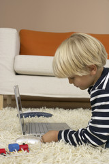 Boy (4-5 Years) lying on floor and using a laptop