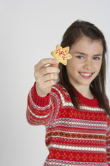 Girl holding a Christmas cookie at camera