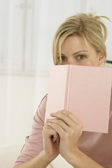 Woman covering her face with book 