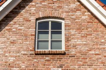 Fototapeta na wymiar Fenster in einer Hauswand unter dem Dach