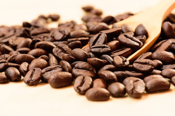 Coffee beans and wooden scoop on wooden background.