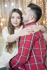 Young future parents on the background of bright lights of garlands.