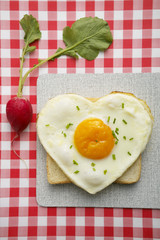 Heart-shaped fried egg on toast and radish