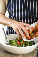 Mature man preparing a salad with strawberries