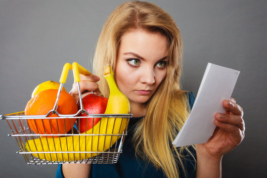 Worried woman holding shopping basket with fruits