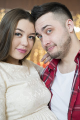 Young future parents on the background of bright lights of garlands.