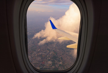 Clouds and sky as seen through window of an aircraft. Looking through window aircraft during flight in wing with a nice blue/purple/orange sky.