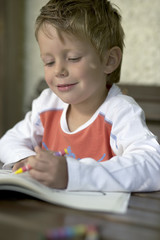 Little boy is drawing into a copybook, selective focus
