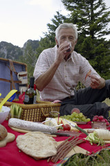 Senior adult man is having a picnic on a meadow, selective focus