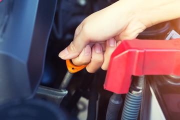 Asian woman's hand checking level of lubricant oil of car engine.