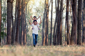 Fototapeta premium Father and daughter having fun and playing in the park and child sits on the shoulders of her father in vintage color tone