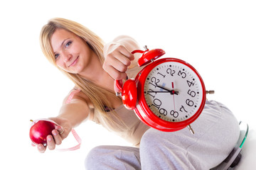 Woman holding apple, measuring tape and clock