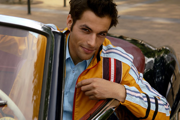 Young man with black hair sitting in a car and looking flirty, close-up