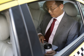 Businessman using laptop in a car
