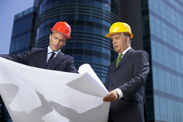 Two Businessman with hardhats watching a plan