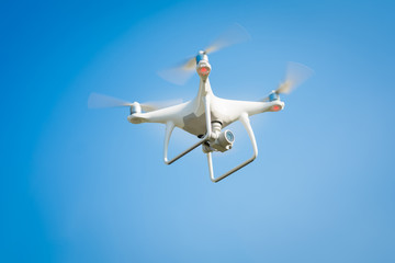 Fototapeta na wymiar white drone hovering in a bright blue sky