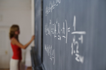 Woman writing arithmetic's on a blackboard, selective focus