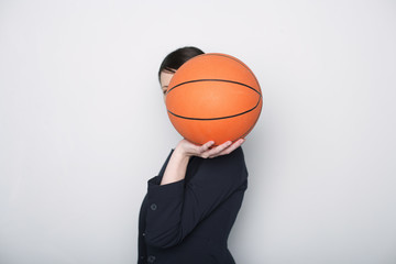 Businesswoman covering face with a basketball