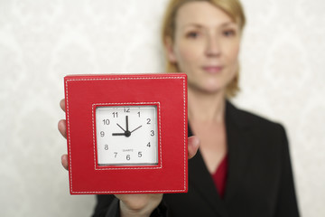 Businesswoman holding at clock at camera