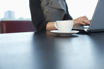 Businesswoman using a laptop, cup of coffee in foreground