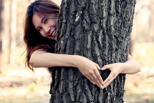 woman hands making a heart shape around a big tree as love nature concept in vintage color tone