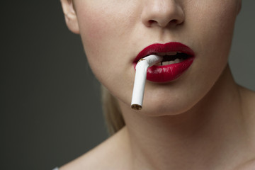 Young woman with a broken cigarette in her mouth (part of), close-up