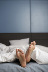 Bare feet of a woman peering out of the blanket, selective focus