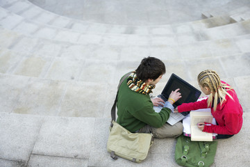 Obraz na płótnie Canvas Young couple using a laptop on a staircase